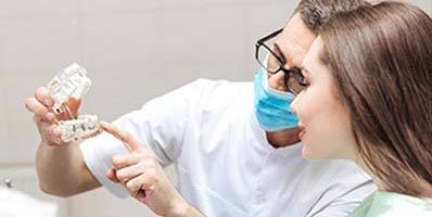 A dentist showing a female patient how dental implants work in Carmichael