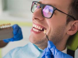 A shade guide being used to match a patient’s dental implant to his natural teeth in Carmichael