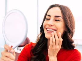 A woman admiring her new smile thanks to dental implants in Carmichael