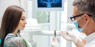 Dentist using model to explain details of how dental implants work