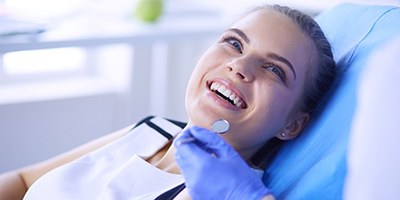 Young woman in dental chair smiling at oral surgeon