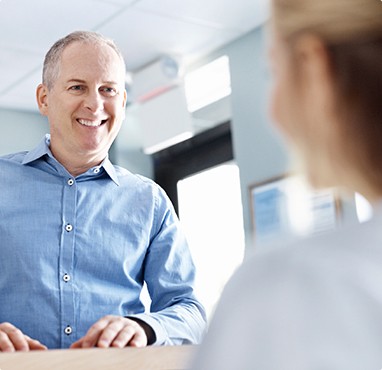 Man smiling at receptionist in oral surgery office