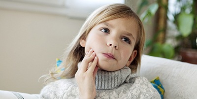 Child rubbing jaw due to impacted tooth pain