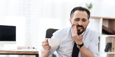 man with severe dental pain after drinking hot tea  