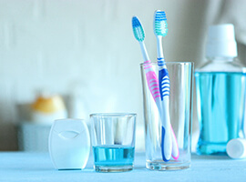 Two toothbrushes, mouthwash, and flossing sitting on countertop