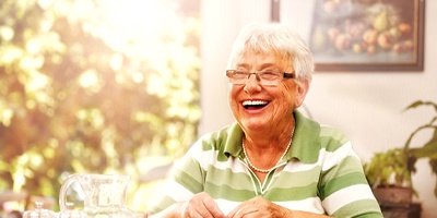 Senior woman eating meal, enjoying benefits of implant dentures