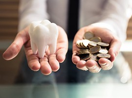 Cost of dental implants in Carmichael demonstrated by hands holding tooth and coins