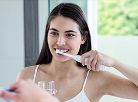 Woman caring for her dental implants in Carmichael by brushing