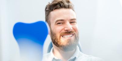 Man smiling and looking at teeth in a mirror