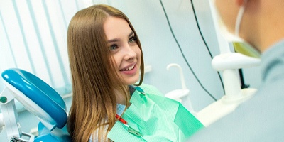Girl in dental chair talking to her dentist