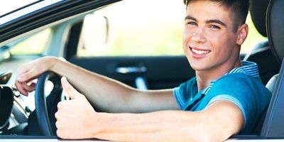 Young man in car giving thumbs up