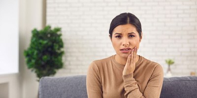 woman putting hand on painful cheek  