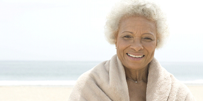 Senior woman with implant dentures smiling on a beach