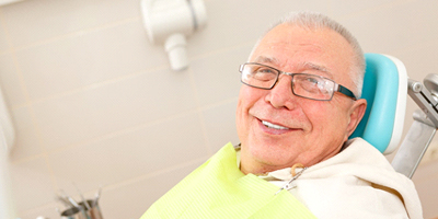 Older man with glasses sitting in dentist’s chair