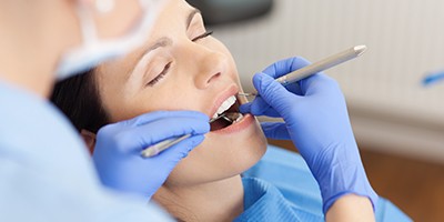 Woman with eyes closed receiving dental treatment