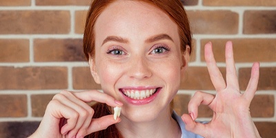 Happy teenager holding wisdom tooth after extraction surgery