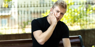 Man on park bench in need of emergency dentistry