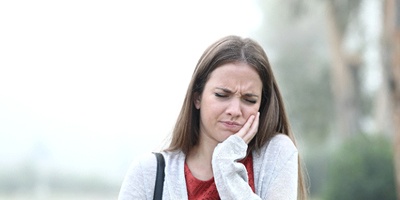 Young woman experiencing painful symptoms of TMJ dysfunction