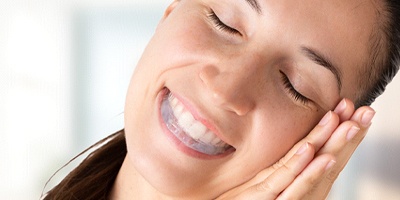 Woman with occlusal splint/nightguard preparing to sleep