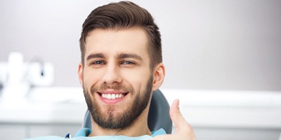 Young man giving thumbs up for occlusal adjustment treatment