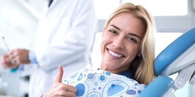 Smiling woman giving thumbs up in dental chair