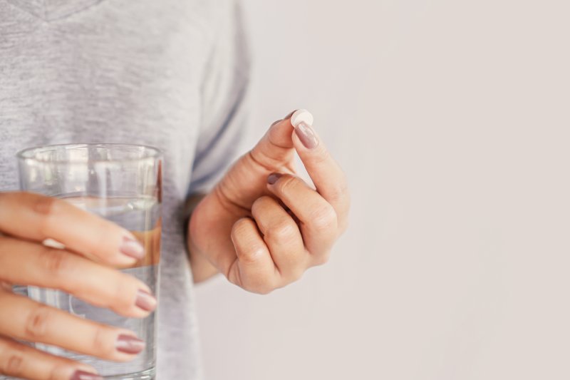 Woman holding a pill and glass of water