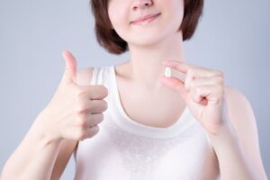 Woman holding her extracted tooth and making thumbs up gesture