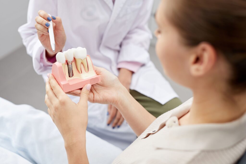 Dentist pointing to sample implant held by patient