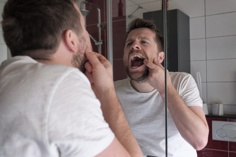 Man looking in mirror at wisdom teeth