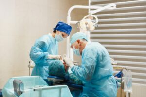 Two dentists performing oral surgery on patient in dentist’s chair.